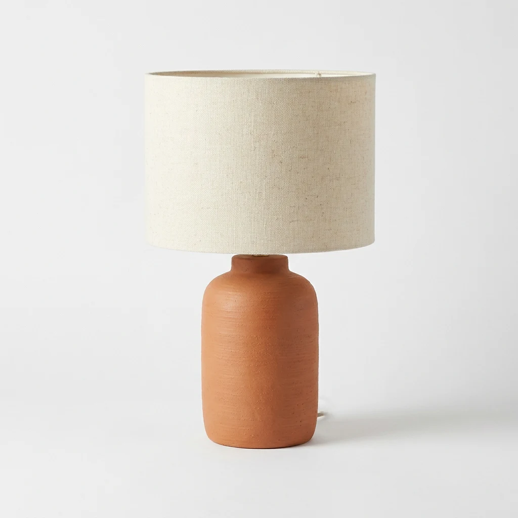 A plain, straight-on studio photo of a terracotta table lamp with a linen shade, the starting point for every styled version