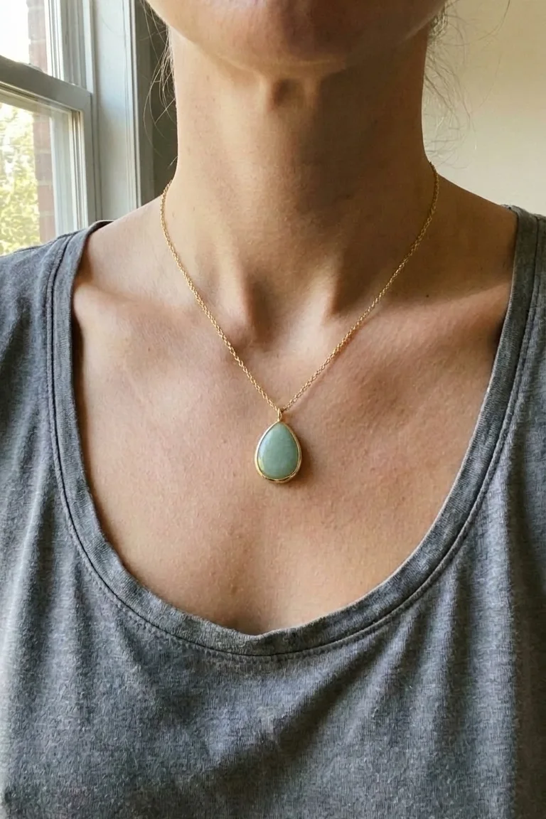 A 2:3 Pinterest pin crop: the green teardrop pendant worn at a neckline over a grey vest top, in daylight